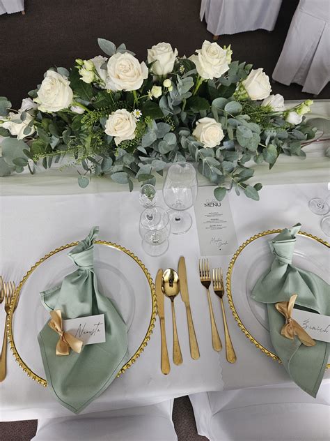 svadobný stôl s bielym saténovým obrusom, kvetmi a sviečkami