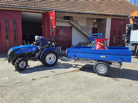 Malotraktor s pripojeným mulčovačom pracujúci na poli.