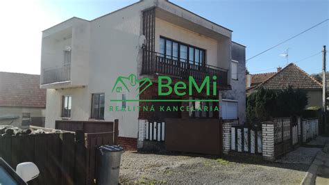 Exteriér rodinného domu s hospodárskou budovou a záhradou.