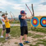 Deti s radosťou strieľajú z luku na farebný terč.