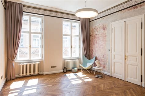 Interiér bytu v historickej budove s vysokými stropmi a štukovými prvkami