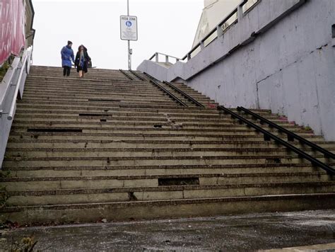 Skupina ľudí sťahujúca chladničku po schodoch pomocou popruhov