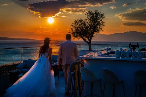 Dvojica kráčajúca po pláži pri západe slnka