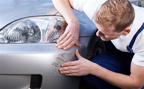 Pracovník merajúci hrúbku laku na automobile