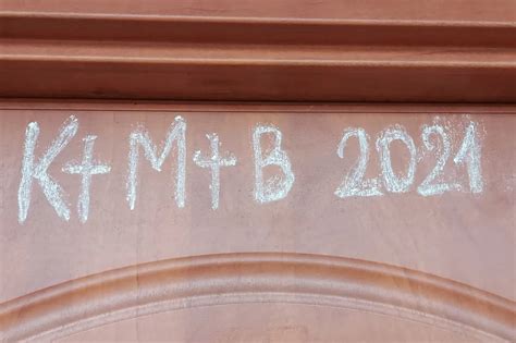 Kriedou napísaný nápis C+M+B na drevených dverách