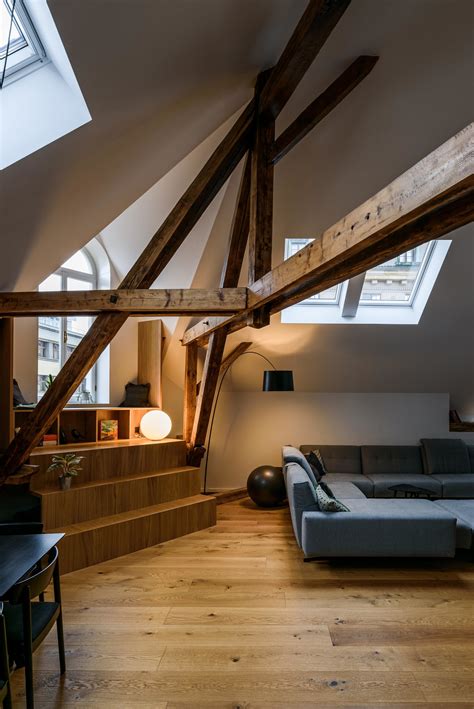 Interiér podkrovného bytu s priznanými trámami a zimnou záhradou