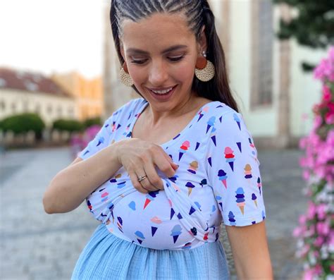 Žena si prezerá svoje prsia v zrkadle, s jemným úsmevom.