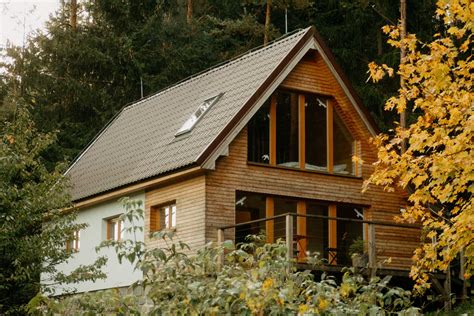 Fotografia chaty v lese s drevenou fasádou a oknami s výhľadom na zeleň
