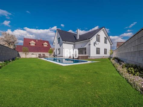 Fotografia rodinného domu s upravenou záhradou a bazénom