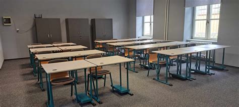 Interiér virtuálnej učebne s lavicami a učiteľským stolom.