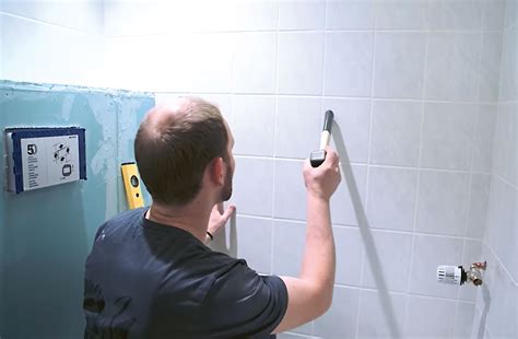 Pracovník osekáva starý obklad z kúpeľňovej steny